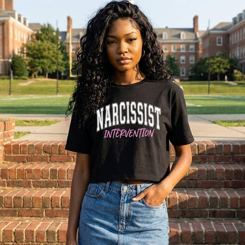 Person wearing a black t-shirt with 'Narcissist Intervention' text on a college campus.