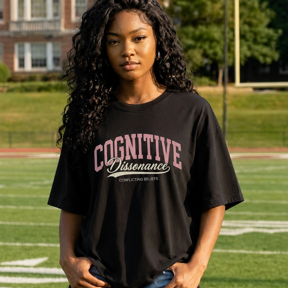 Person wearing a black t-shirt with 'Cognitive Dissonance' text on a grassy field.