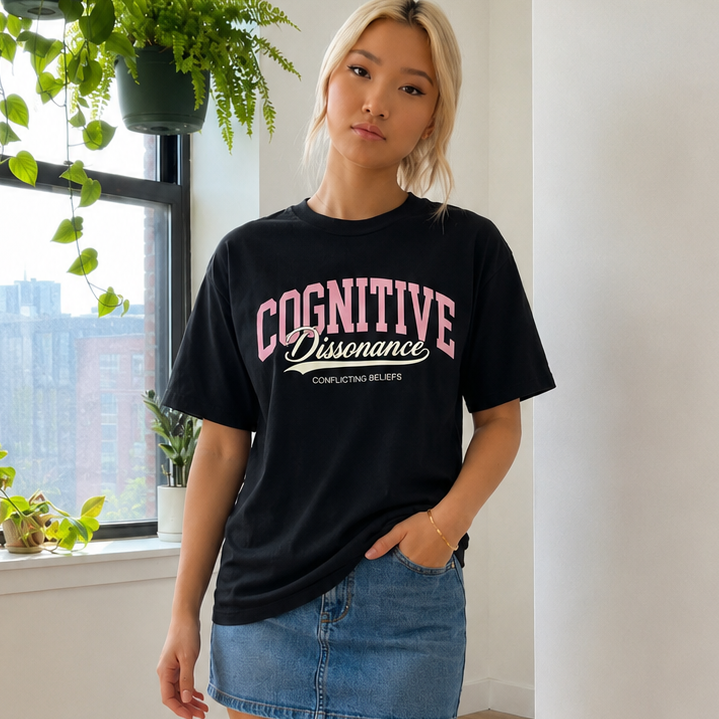Person wearing a black t-shirt with cognitive dissonance in a room with plants and a window.